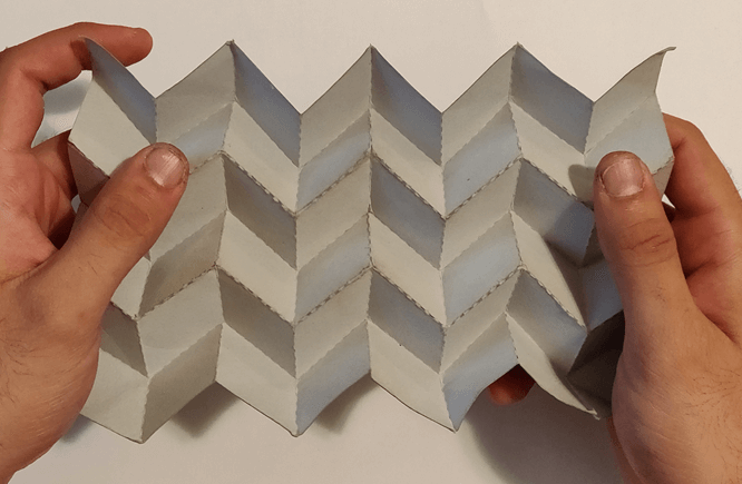 Small scale paper mockup of the origami pattern stretched by two hands