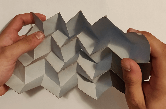 Small scale paper mockup of the origami pattern stretched by two hands