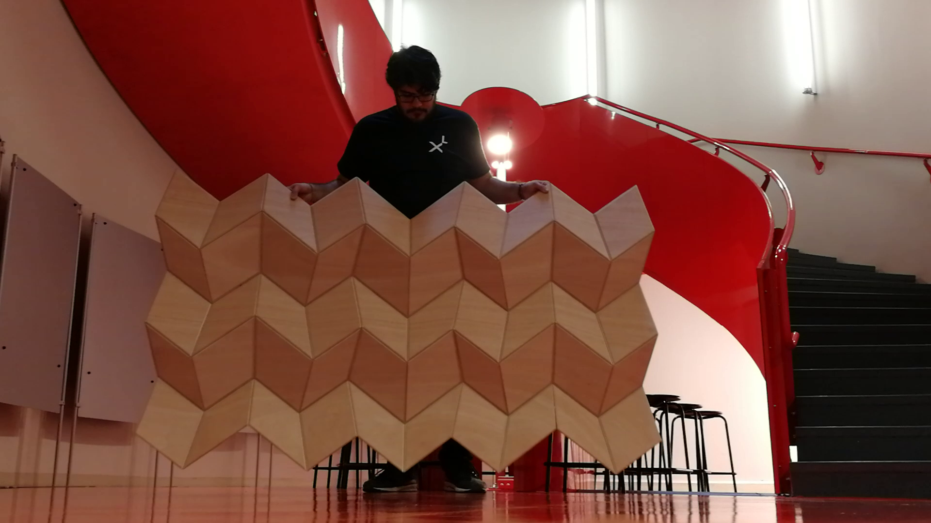 Prototype of the Shifting Folds wooden origami held by a man